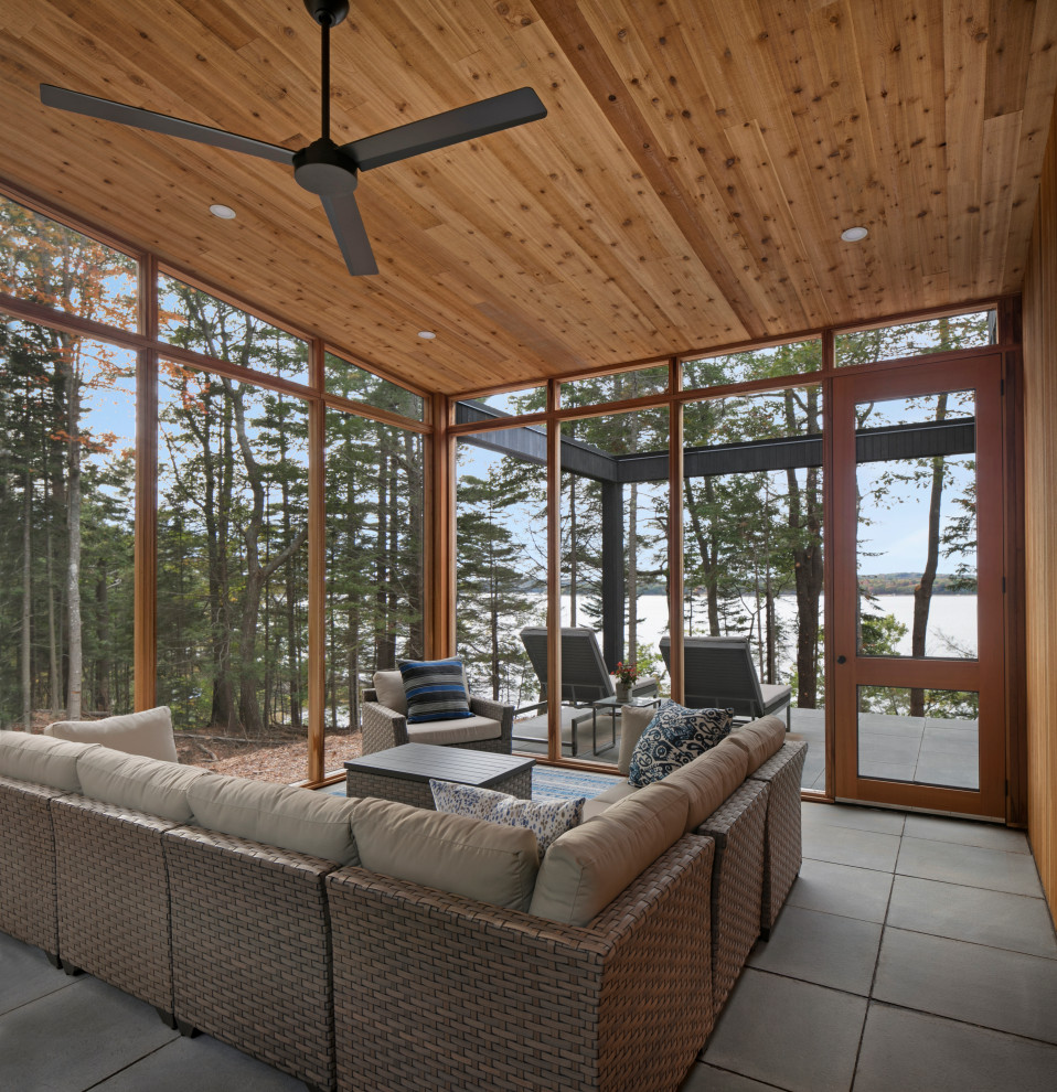Large mountain style concrete paver screened-in side porch idea in Portland Maine with a roof extension