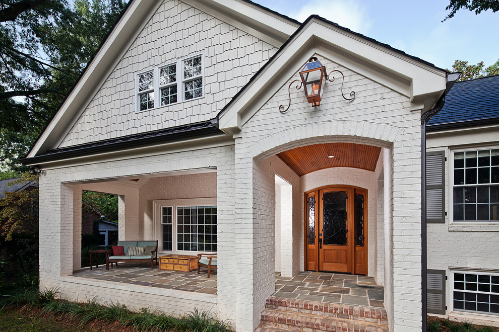 Foto di un portico classico di medie dimensioni e davanti casa con pavimentazioni in pietra naturale e un tetto a sbalzo