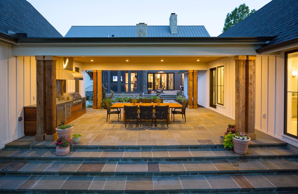 Пример оригинального дизайна: веранда на заднем дворе в стиле кантри с летней кухней, покрытием из каменной брусчатки и навесом
