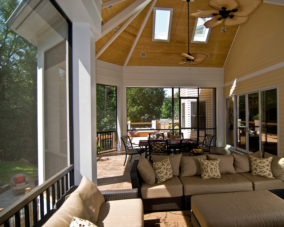 This is an example of a mid-sized traditional tile screened-in back porch design in Charlotte with a roof extension.