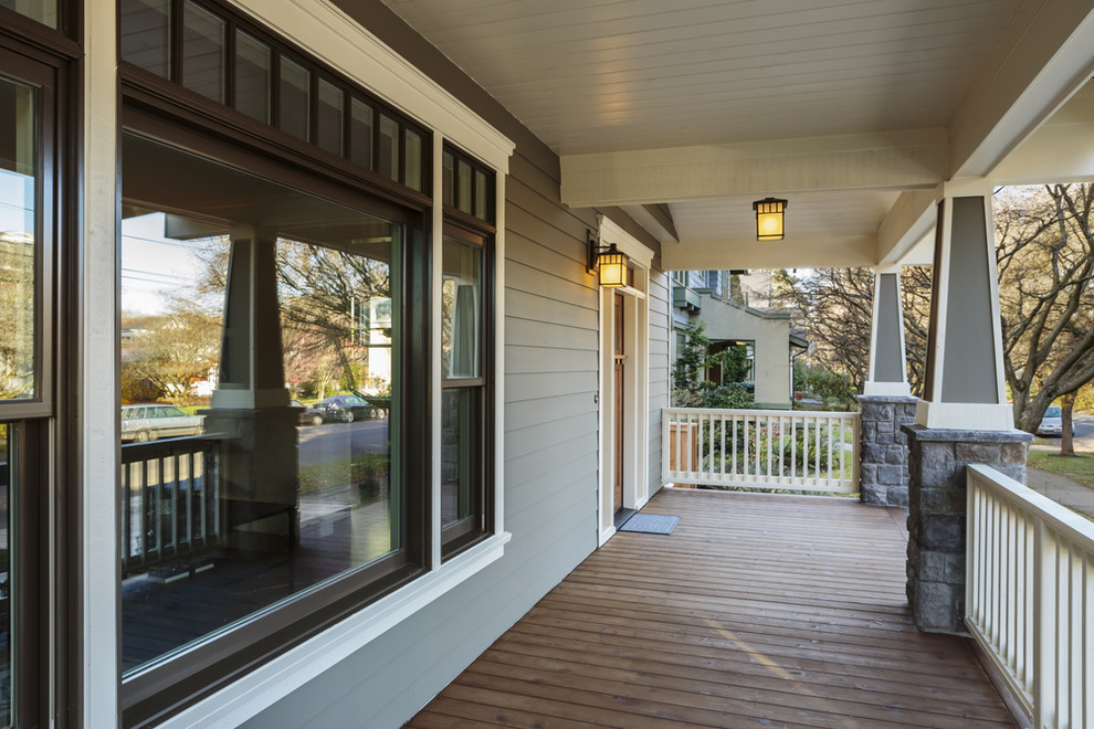 Bild på en mellanstor amerikansk veranda framför huset, med trädäck och takförlängning