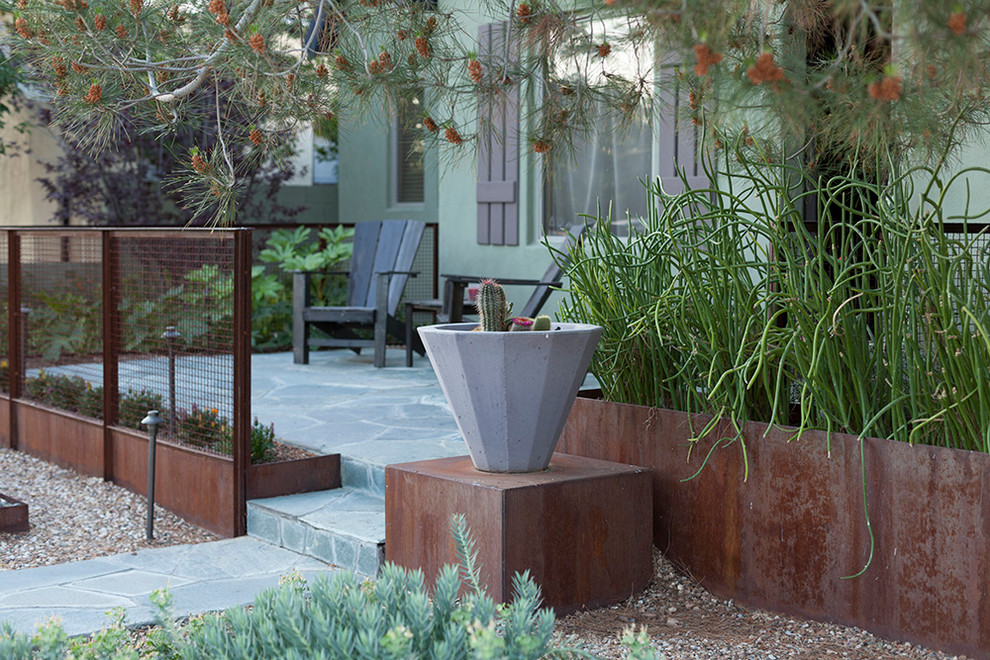Ejemplo de terraza industrial de tamaño medio en patio delantero con adoquines de piedra natural