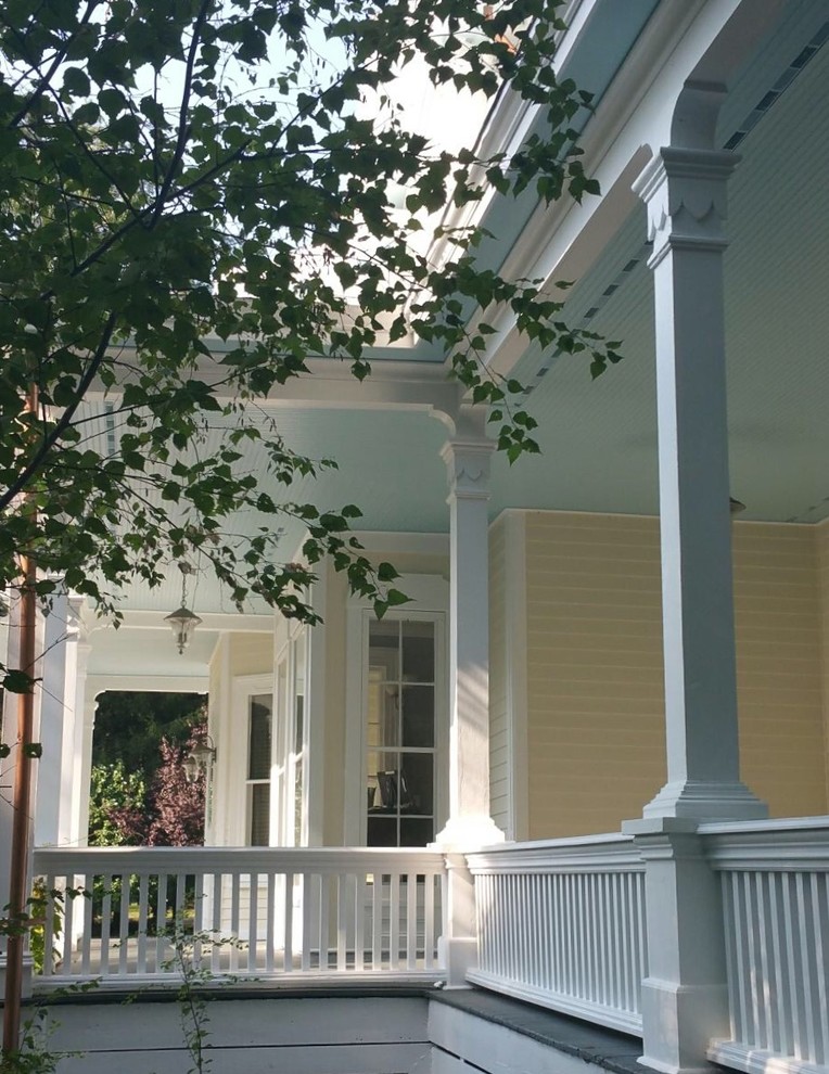 This is an example of a large traditional front porch design in Other with a roof extension.