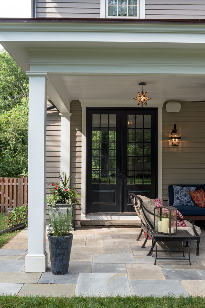 Idées déco pour un porche d'entrée de maison avant classique avec des pavés en pierre naturelle et une extension de toiture.