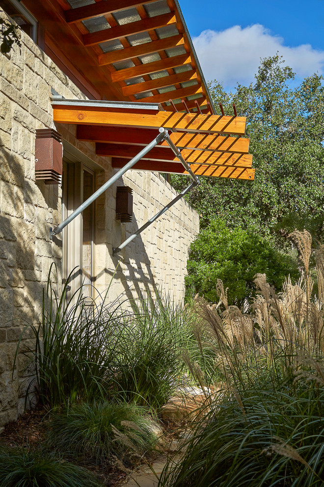 This is an example of a large stone porch design in Austin with an awning.