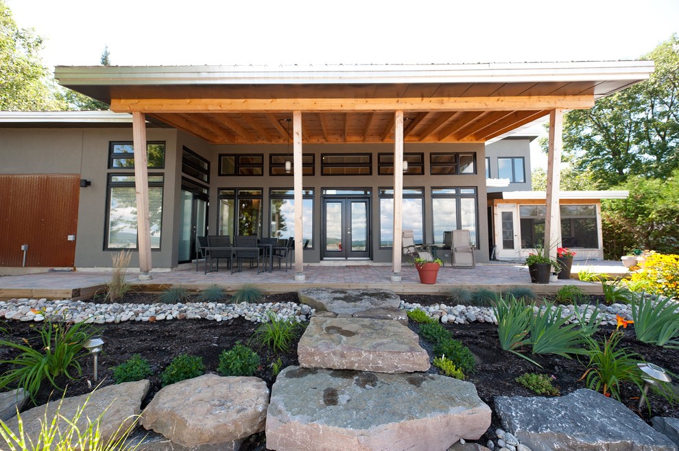 Bild på en mellanstor funkis veranda på baksidan av huset, med naturstensplattor och en pergola