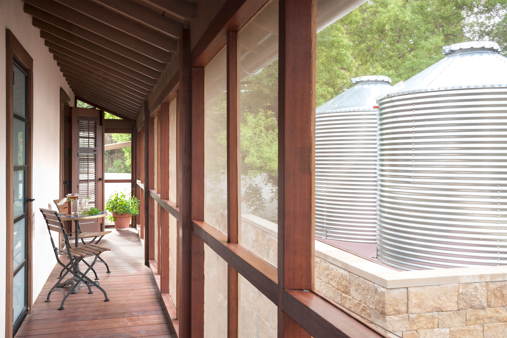 This is an example of a small rustic back screened veranda in Austin with a roof extension.