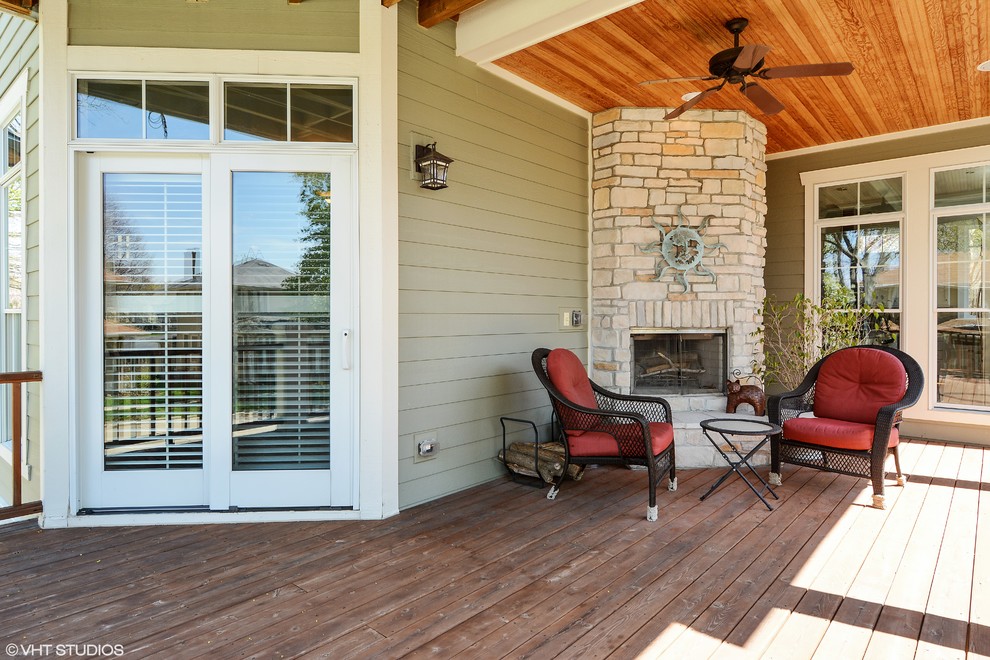 Inspiration pour un grand porche d'entrée de maison avant craftsman avec un foyer extérieur, une terrasse en bois et une extension de toiture.