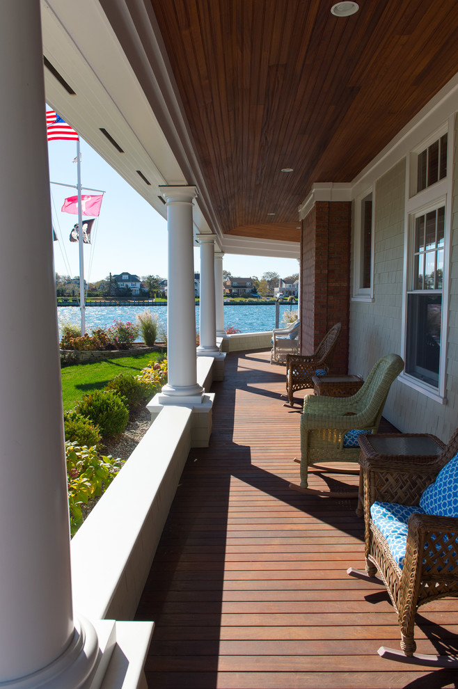 Exemple d'un grand porche d'entrée de maison avant bord de mer avec une terrasse en bois et une extension de toiture.