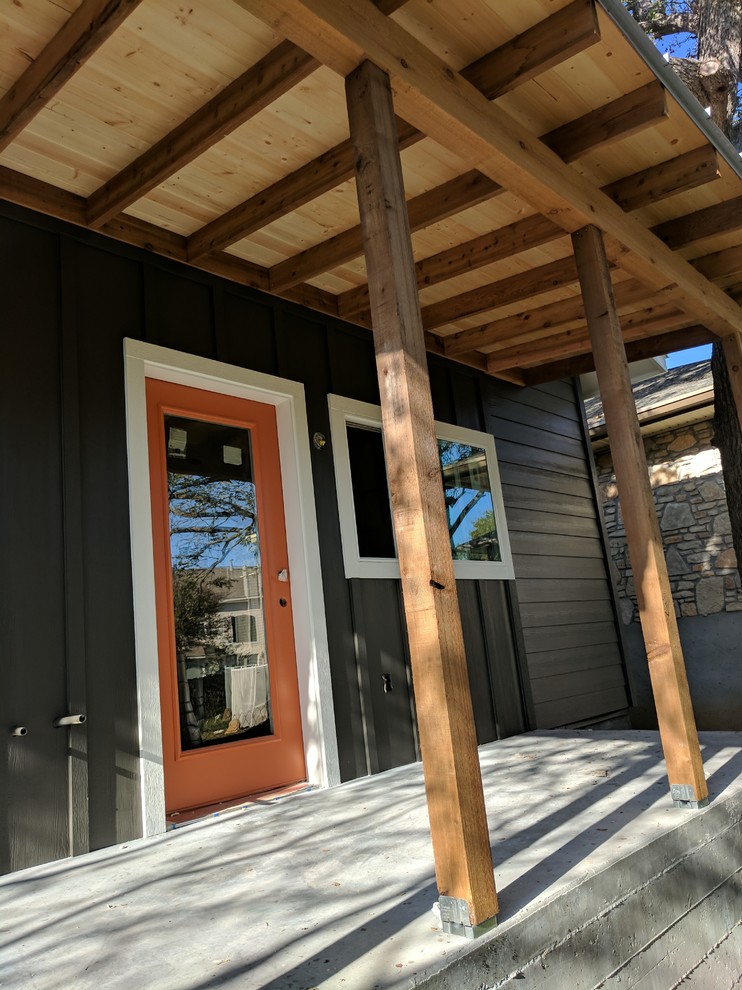 Modern inredning av en mellanstor veranda framför huset, med betongplatta och takförlängning