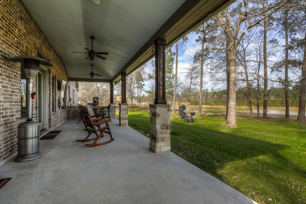 Photo of a large rural back veranda in Houston with an outdoor kitchen, concrete slabs and a roof extension.