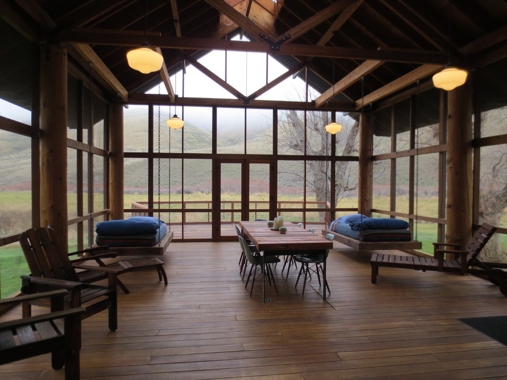 Cette photo montre un porche d'entrée de maison montagne avec une terrasse en bois, une extension de toiture et une moustiquaire.