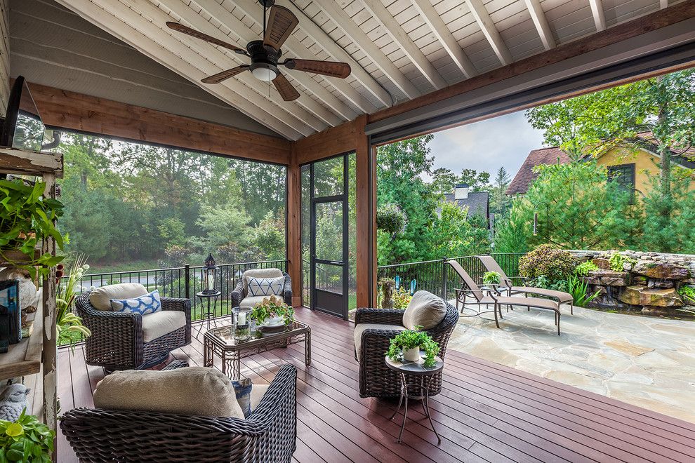 Aménagement d'un grand porche d'entrée de maison arrière avec une moustiquaire, une terrasse en bois et une extension de toiture.