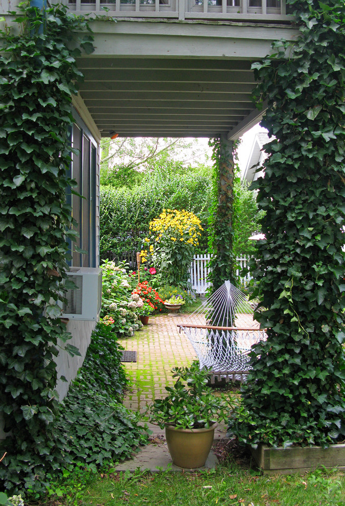 Imagen de terraza rural de tamaño medio en patio trasero y anexo de casas con jardín vertical y adoquines de ladrillo