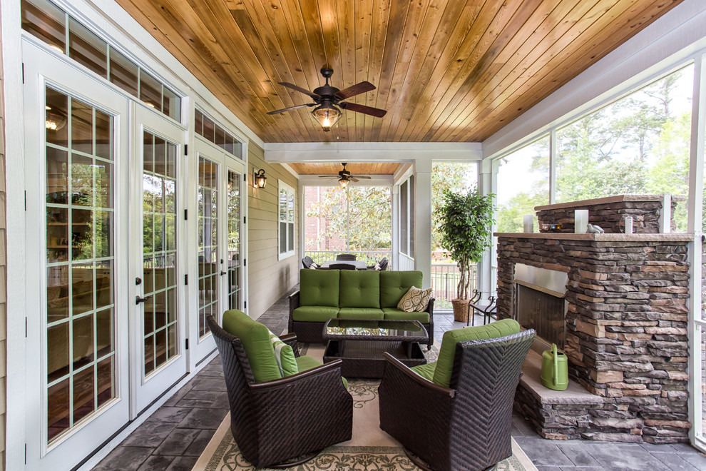 Cette photo montre un grand porche d'entrée de maison arrière tendance avec un foyer extérieur, des pavés en béton et une extension de toiture.