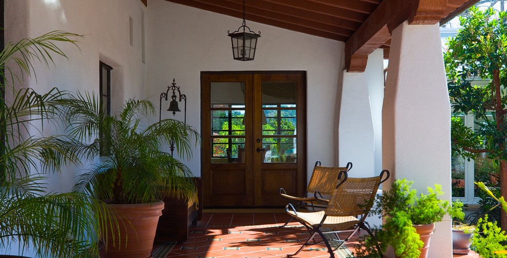 Inspiration for a mediterranean tile porch remodel in Orange County with a roof extension