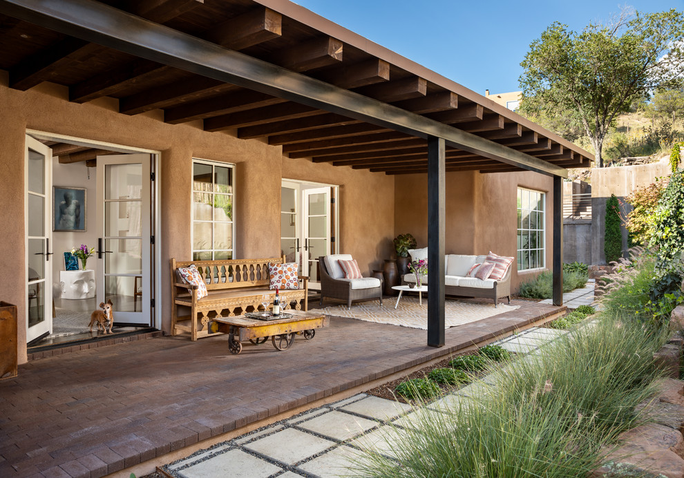 Cette photo montre un porche d'entrée de maison arrière sud-ouest américain de taille moyenne avec des pavés en brique et une extension de toiture.