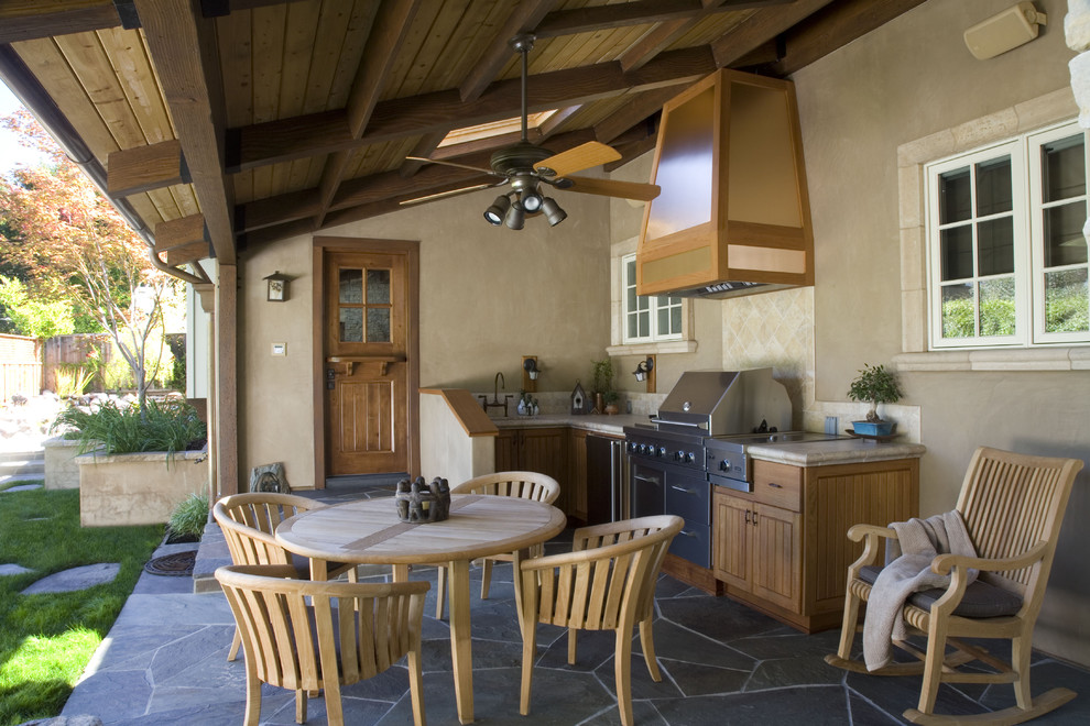 This is an example of a traditional stone outdoor kitchen porch design in San Francisco with a roof extension.