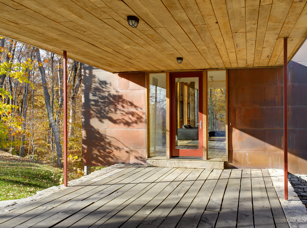 Cette image montre un porche d'entrée de maison minimaliste avec une terrasse en bois et une extension de toiture.