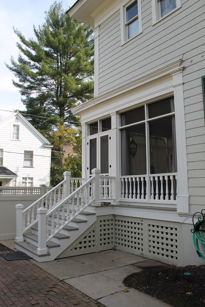 This is an example of a mid-sized traditional screened-in back porch design in Other with a roof extension and decking.