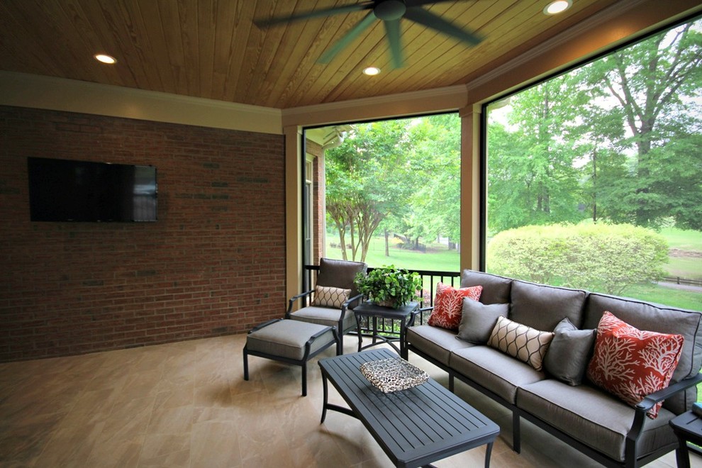 This is an example of a large traditional stone screened-in back porch design in Charlotte with a roof extension.