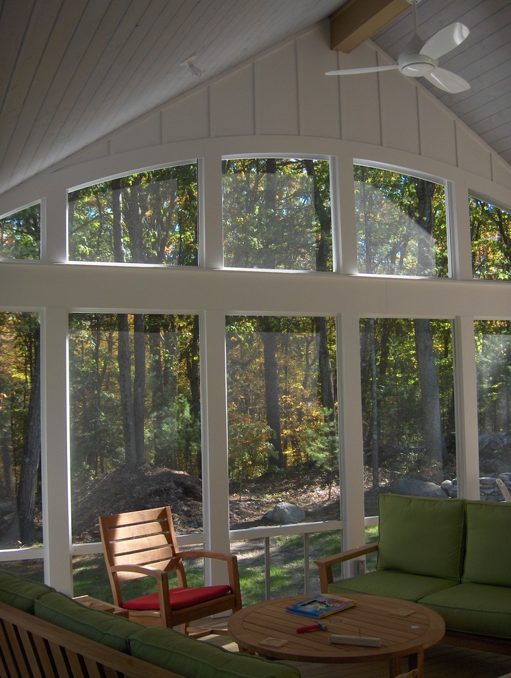 This is an example of a large eclectic screened-in back porch design in Boston with decking and a roof extension.