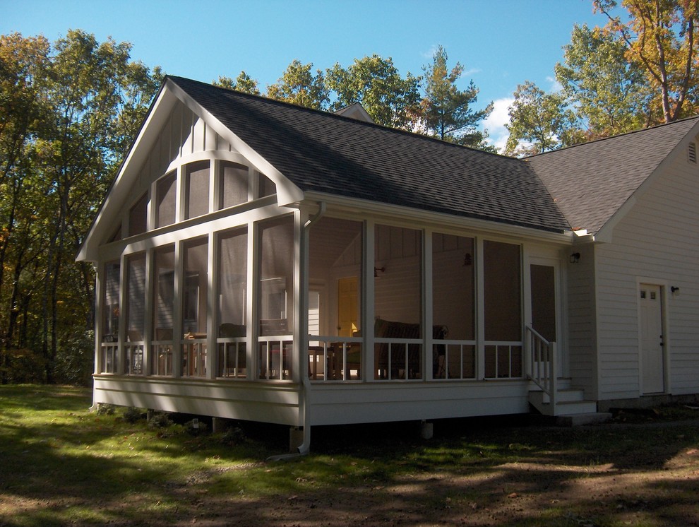 Cette photo montre un grand porche d'entrée de maison arrière éclectique avec une moustiquaire et une extension de toiture.