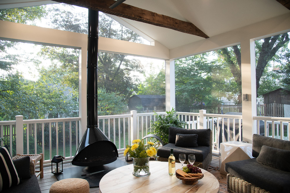 This is an example of a mid-sized transitional screened-in back porch design in DC Metro with a roof extension.