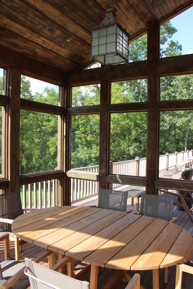 Rustik inredning av en mellanstor innätad veranda, med trädäck och takförlängning