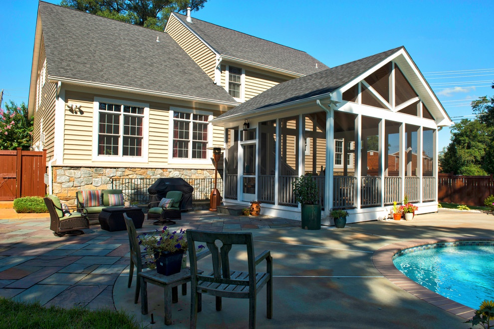 Photo of a large classic back screened veranda in DC Metro with stamped concrete and a roof extension.