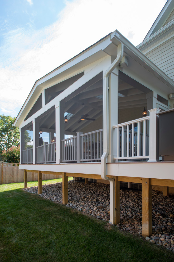 Idée de décoration pour un grand porche d'entrée de maison arrière tradition avec une moustiquaire, une terrasse en bois et une extension de toiture.