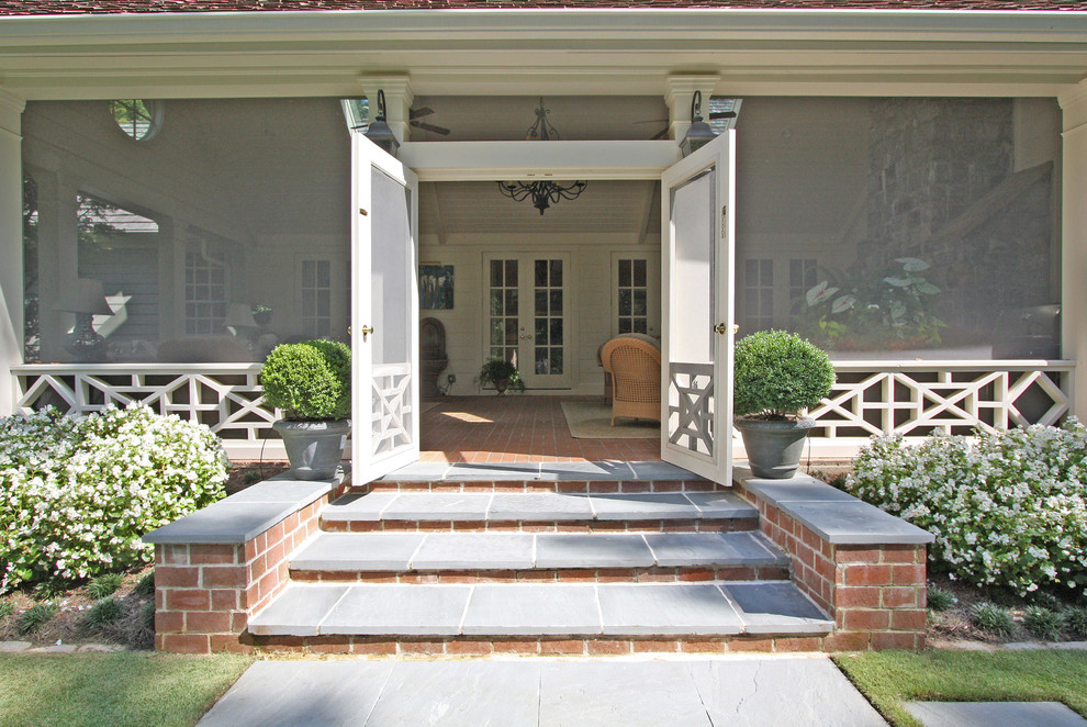 Bild på en mellanstor vintage veranda på baksidan av huset, med marksten i tegel och takförlängning