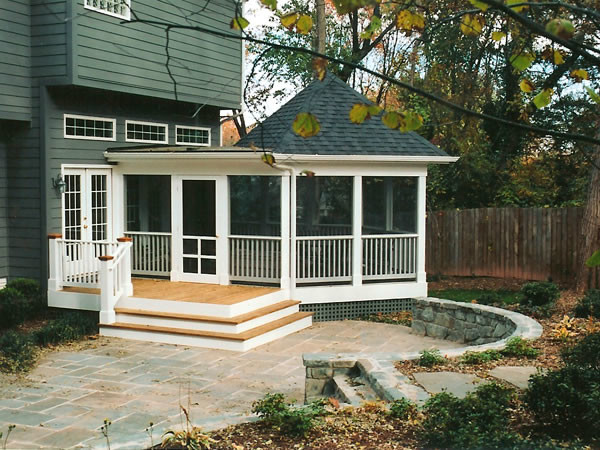 Diseño de porche cerrado actual de tamaño medio en patio trasero y anexo de casas con entablado