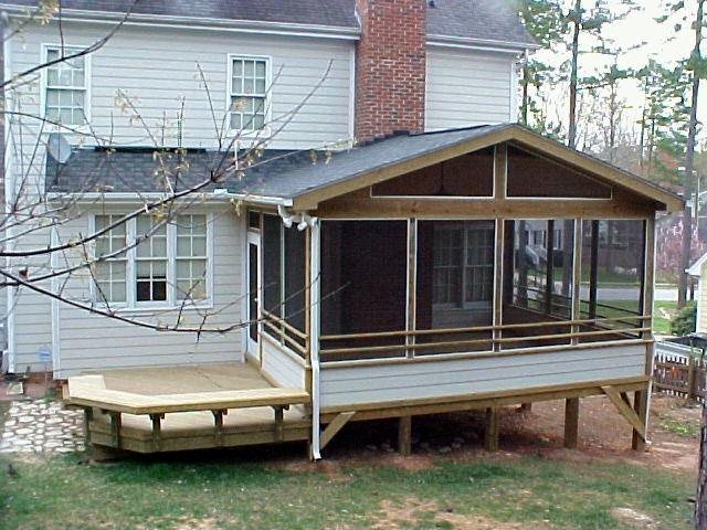 Cette image montre un grand porche d'entrée de maison arrière avec une moustiquaire, une terrasse en bois et une extension de toiture.