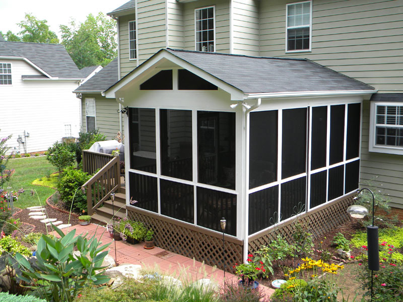 Idée de décoration pour un porche d'entrée de maison arrière avec une moustiquaire, une terrasse en bois et une extension de toiture.