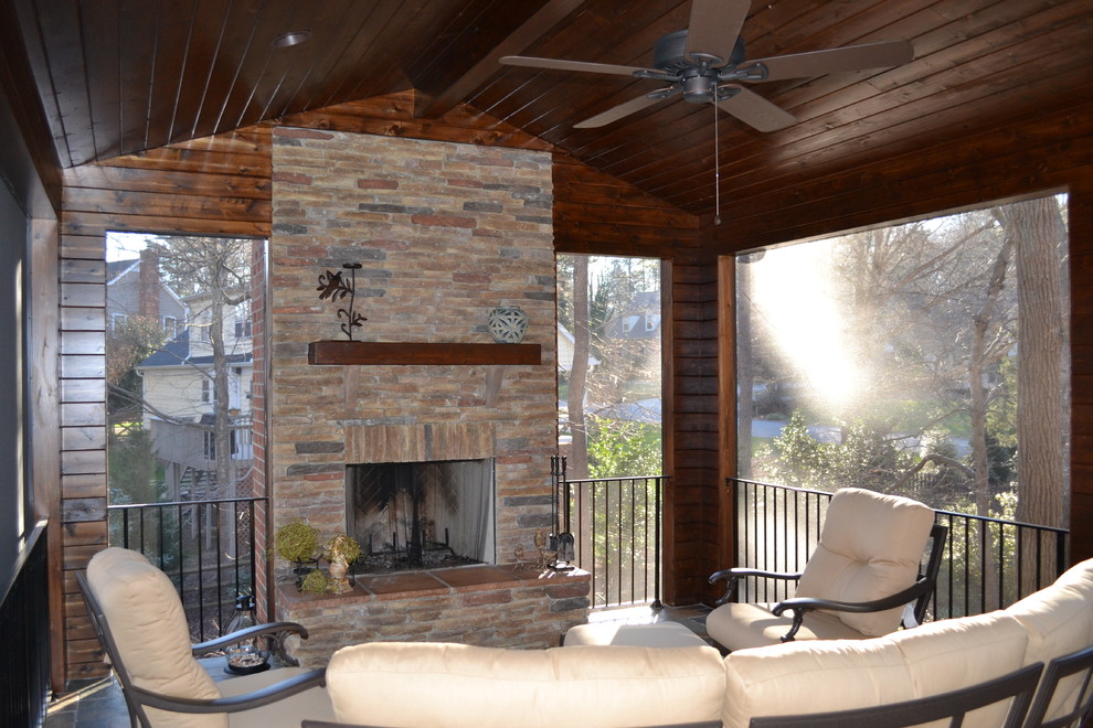 This is an example of a craftsman stone screened-in back porch design in Charlotte with a roof extension.