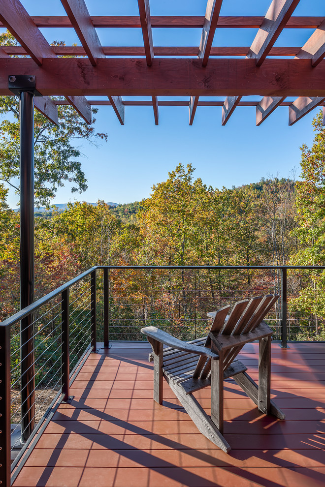 Cette photo montre un grand porche d'entrée de maison arrière montagne avec du carrelage et une pergola.