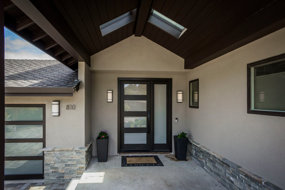 Exemple d'un grand porche d'entrée de maison avant tendance avec une dalle de béton et une extension de toiture.