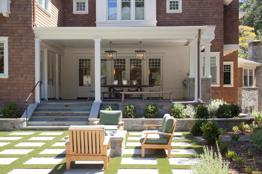 Foto di un portico american style dietro casa con pavimentazioni in pietra naturale, un tetto a sbalzo e con illuminazione