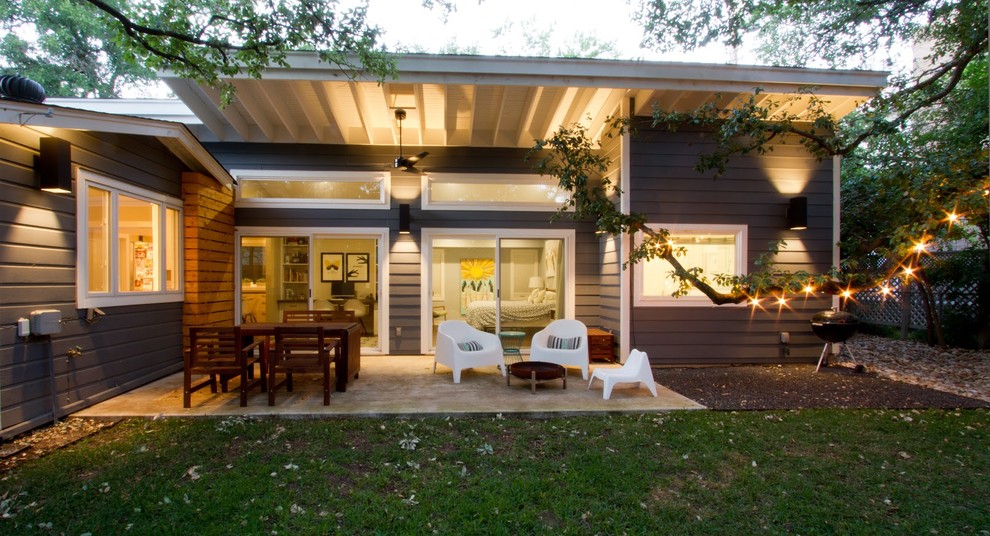 Medium sized modern back veranda in Austin with concrete slabs, a roof extension and a fire feature.