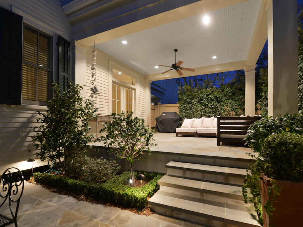 Inspiration for a mid-sized timeless stone back porch remodel in New Orleans with a roof extension
