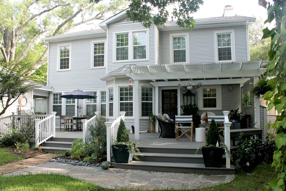 Exemple d'un grand porche d'entrée de maison arrière craftsman avec une terrasse en bois et une pergola.