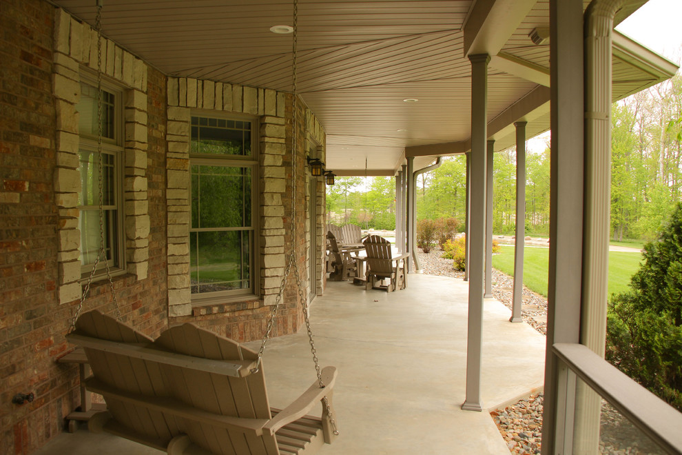 Idée de décoration pour un très grand porche d'entrée de maison latéral chalet avec une dalle de béton et une extension de toiture.