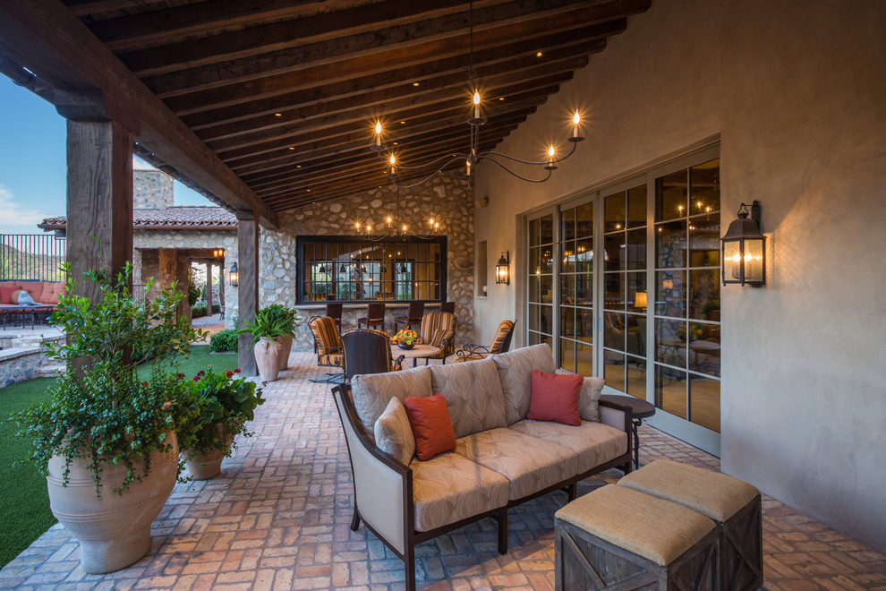 Photo of an expansive mediterranean back veranda in Phoenix with brick paving, a roof extension and a bar area.
