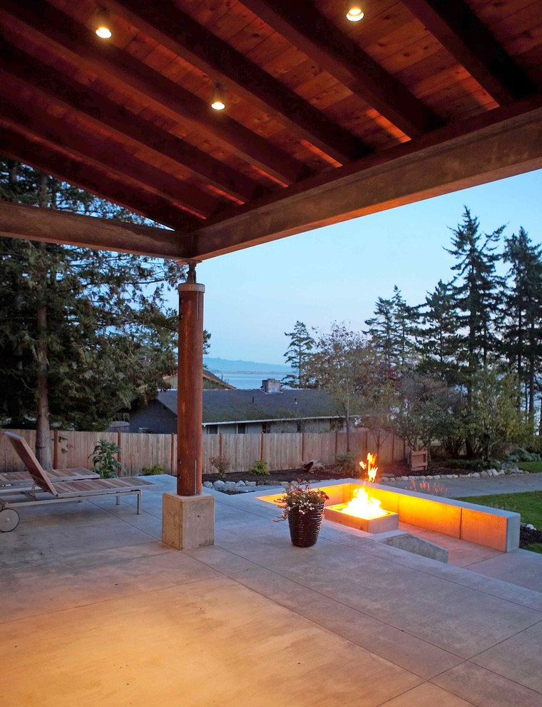 This is an example of a medium sized modern front veranda in Seattle with a fire feature, concrete slabs and a roof extension.