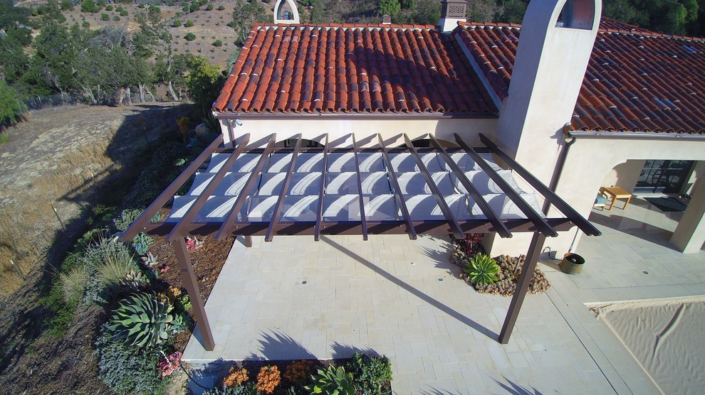 Exemple d'un petit porche d'entrée de maison arrière méditerranéen avec des pavés en pierre naturelle et une pergola.