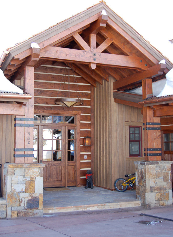 This is an example of a mid-sized rustic stone front porch design in Denver with a roof extension.