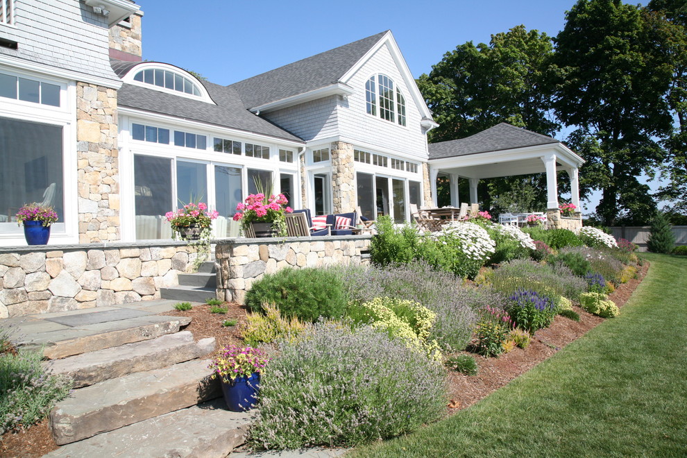 Ejemplo de terraza de estilo americano grande en patio trasero con adoquines de piedra natural