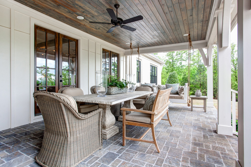 Cette image montre un grand porche d'entrée de maison arrière traditionnel avec des pavés en pierre naturelle et une extension de toiture.