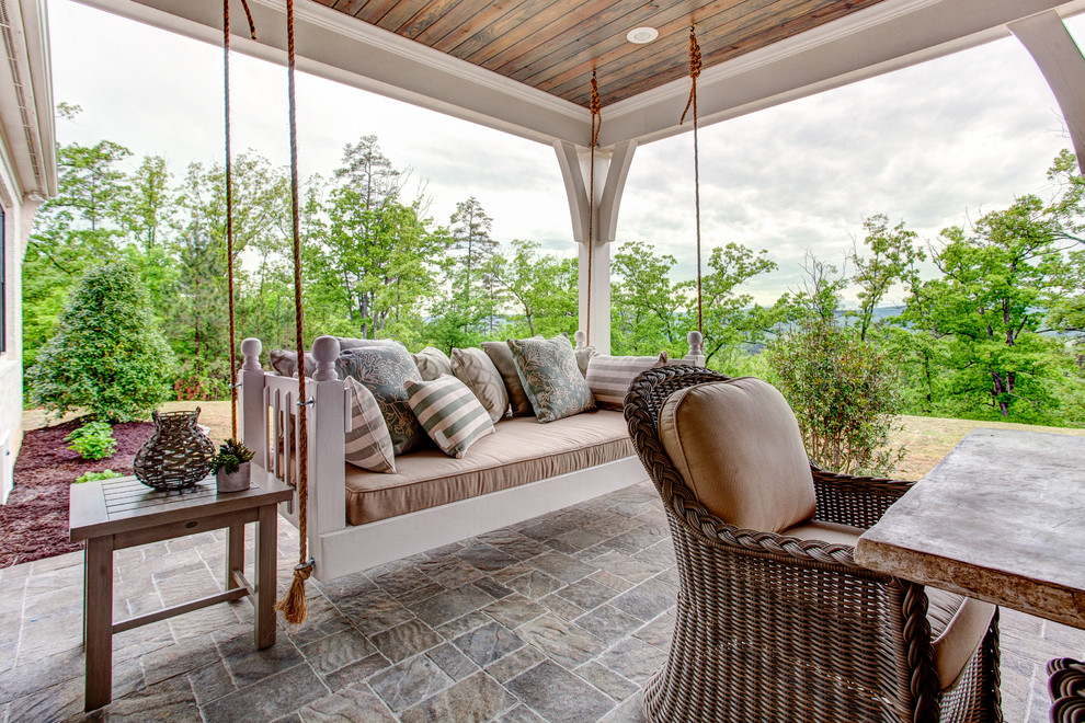 Idée de décoration pour un grand porche d'entrée de maison arrière tradition avec des pavés en pierre naturelle et une extension de toiture.